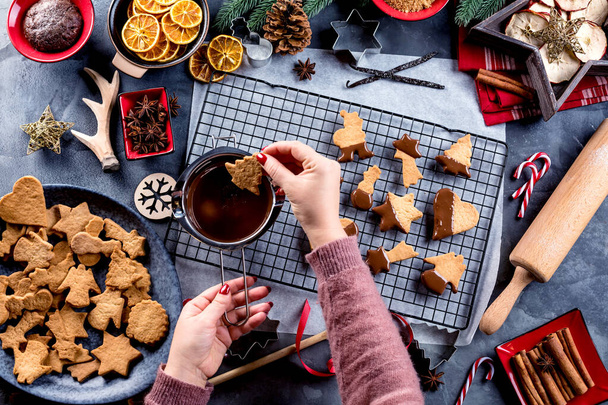 partial top view of woman glazing Christmas biscuits with liquid chocolate on a kitchen table - Photo, image