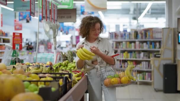 dona de casa segurando cesta de supermercado escolhe alimentos saudáveis frutas frescas na seção de supermercado - Filmagem, Vídeo