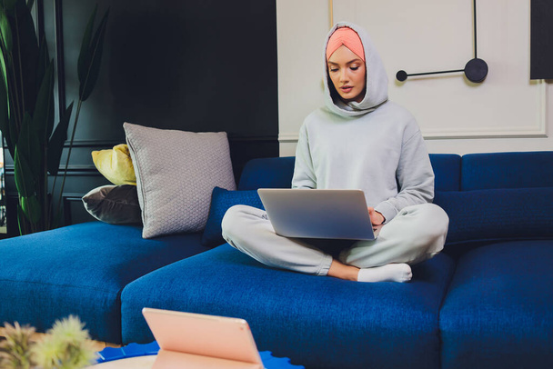 Beautiful Muslim middle-aged woman with laptop at home. - Foto, Bild