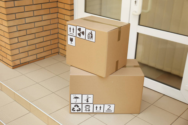 Cardboard boxes with different packaging symbols on floor near entrance. Parcel delivery - Foto, Imagem