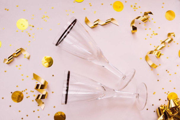 qualidade dois copos limpos vazios para bebidas em um fundo bege delicado claro com um arco de folha dourada, fita, círculos amarelos e espirais de ouro serpentinas - Foto, Imagem