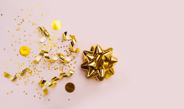 fiocco in lamina d'oro per la decorazione su un delicato sfondo beige con cerchi gialli e spirali in oro serpentino. layout per regali, saluti e vendite. - Foto, immagini