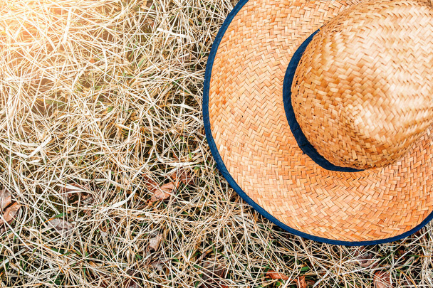 Geniş kenarlı sarı hasır hasır şapka ve yazın kuru çimlerin üzerinde mavi bant.. - Fotoğraf, Görsel