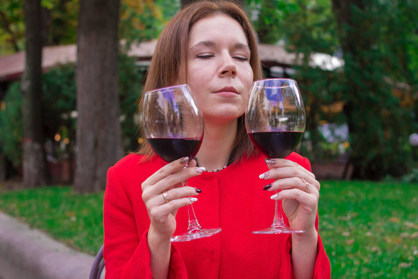 Fille dans un manteau rouge avec un verre de vin rouge - Photo, image