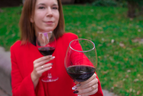 Κορίτσι με κόκκινο παλτό και ποτήρια κόκκινο κρασί - Φωτογραφία, εικόνα