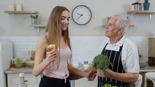 Abuelo mayor con nieta recomendando comer alimentos vegetales crudos. Dieta vegetal - Imágenes, Vídeo