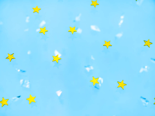 Fényes arany csillagok, kék háttérrel, flitterekkel. Az ünnep fogalma, öröm. Ünnepi háttér a projektekhez - Fotó, kép