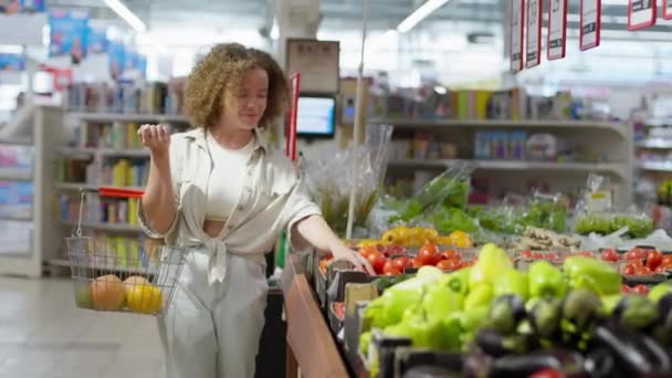 varejo, mulher com cesta em mãos compra legumes frescos e frutas no supermercado - Filmagem, Vídeo