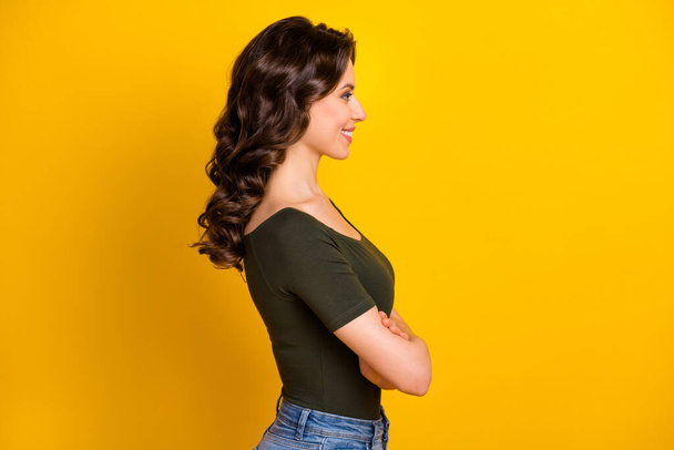 Profile side view portrait of her she nice-looking attractive well-groomed winsome cheerful feminine wavy-haired girl folded arms isolated on bright vivid shine vibrant yellow color background - Photo, image