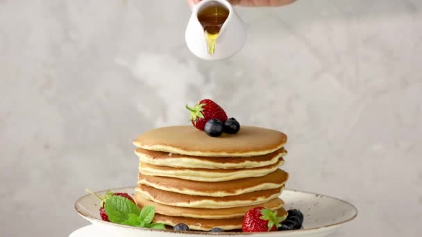 Women hand is pouring syrup from small ceramic jar to pancake with blueberry and mint. Close up. - Footage, Video