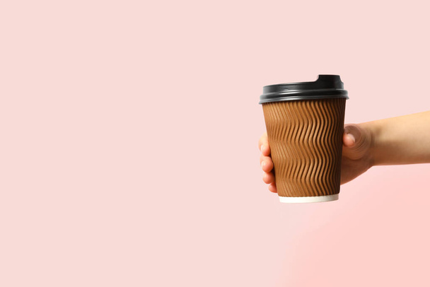 Woman holding takeaway paper coffee cup on pink background, closeup. Space for text - Fotó, kép