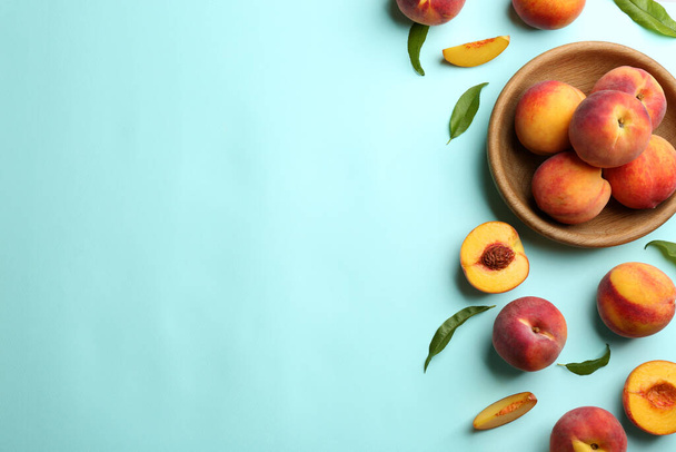 Fresh ripe peaches and green leaves on light blue background, flat lay. Space for text - Photo, Image