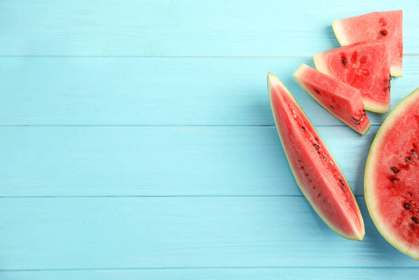 Tasty ripe cut watermelon on light blue wooden table, flat lay. Space for text - Foto, Bild
