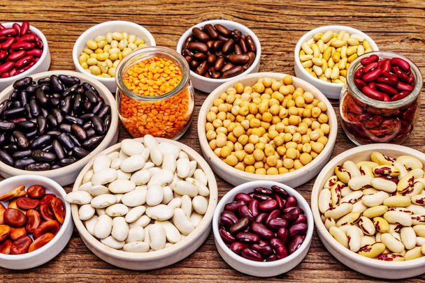 豆の異なる種類を割り当てます。健康的なライフスタイルのための様々な乾燥したマメ科植物、不可欠なタンパク質のセット。ヴィンテージ木製ボードの背景 - 写真・画像