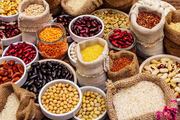 豆や穀物の異なる種類を割り当てます。健康な生活のためのタンパク質の不可欠な源のセット。古い木製のテーブル - 写真・画像