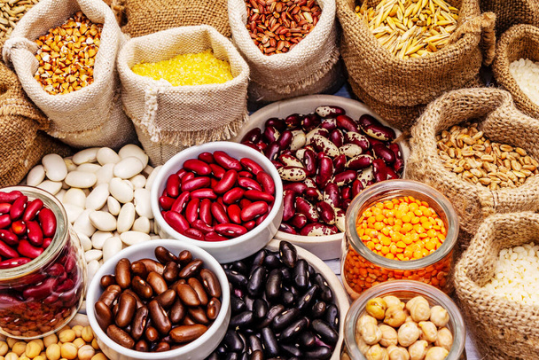 Různé druhy fazolí a obilných zrn. Sada nepostradatelných zdrojů bílkovin pro zdravý životní styl. Bílé dřevěné desky pozadí - Fotografie, Obrázek