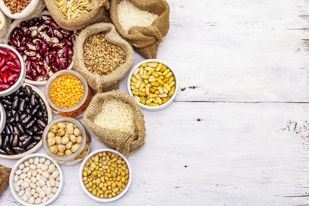 Různé druhy fazolí a obilných zrn. Sada nepostradatelných zdrojů bílkovin pro zdravý životní styl. Bílé dřevěné desky pozadí - Fotografie, Obrázek