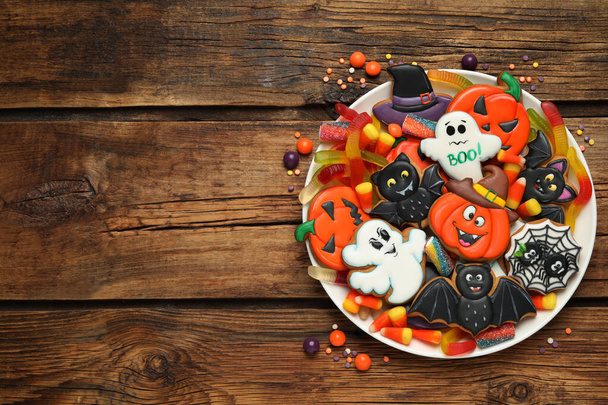 Tasty cookies and sweets for Halloween party on wooden table, top view. Space for text - Фото, изображение