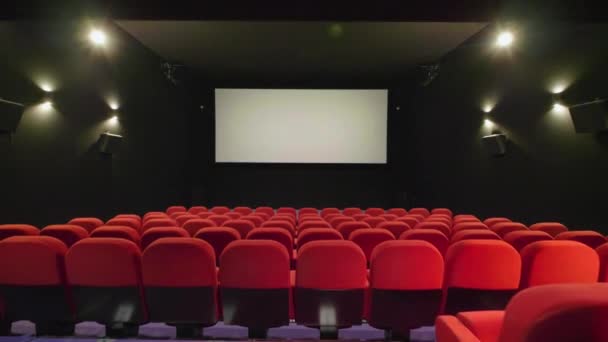 Viajando sobre a fila do assento do cinema vermelho com tela no fundo. Teatro de cinema - Filmagem, Vídeo