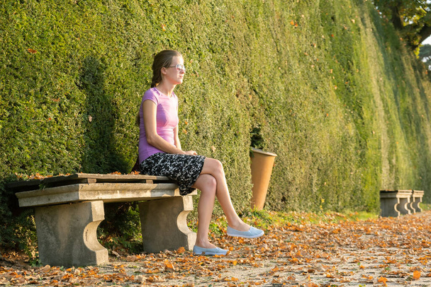 Une femme assise sur un banc dans un parc d'été. - Photo, image