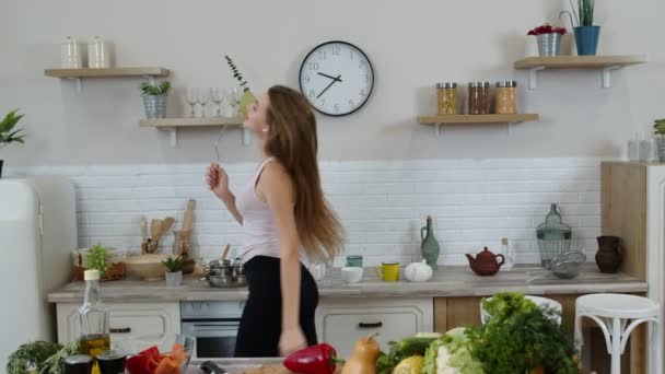 Gelukkig veganistisch meisje met slank taille dansen, zingen in de keuken. Rauwe plantaardige voeding dieet concept - Video