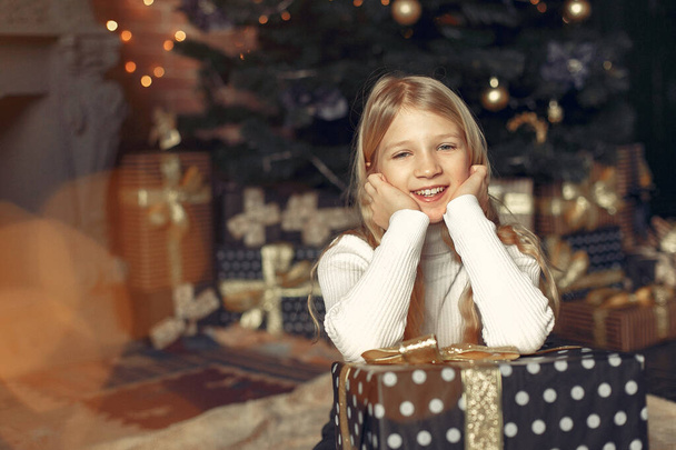 Petite fille dans un pull blanc près de l'arbre de Noël avec présent - Photo, image