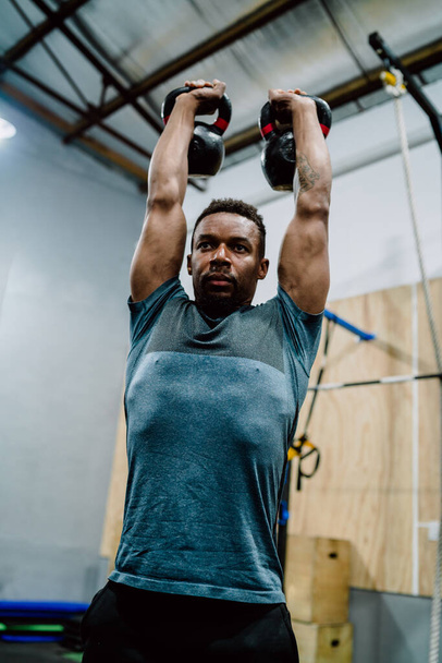 Portrait of young athletic man doing exercise with crossfit kettlebel at the gym. Crossfit, sport and healthy lifestyle concept. - Fotoğraf, Görsel