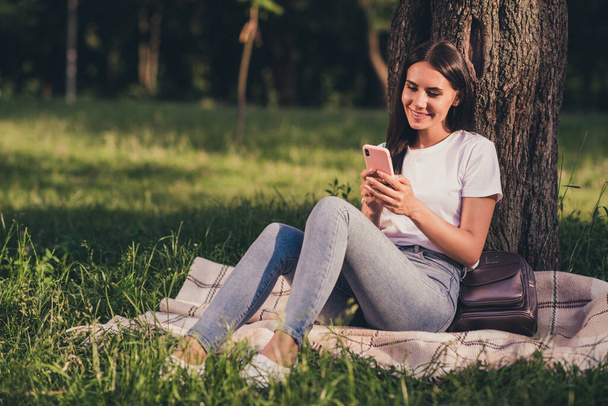 Portrait of her she nice attractive pretty cheerful cheery girl using device gadget app 5g sitting on lawn green color grass veil blanket duvet fresh air spending free spare time - Foto, afbeelding