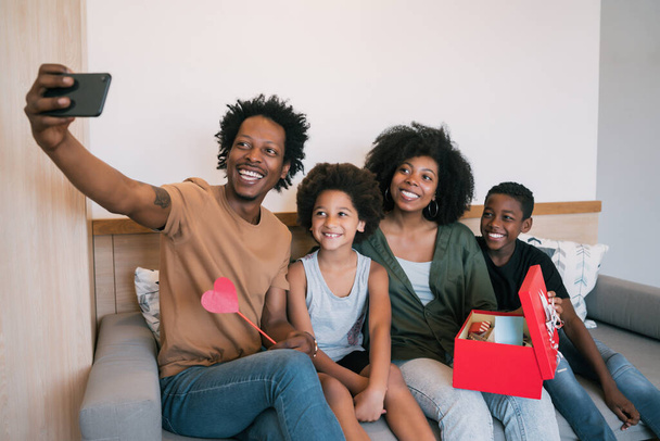 Portrait of African american family taking a selfie with phone while celebrating mother's day at home. Mother's day celebration concept. - 写真・画像