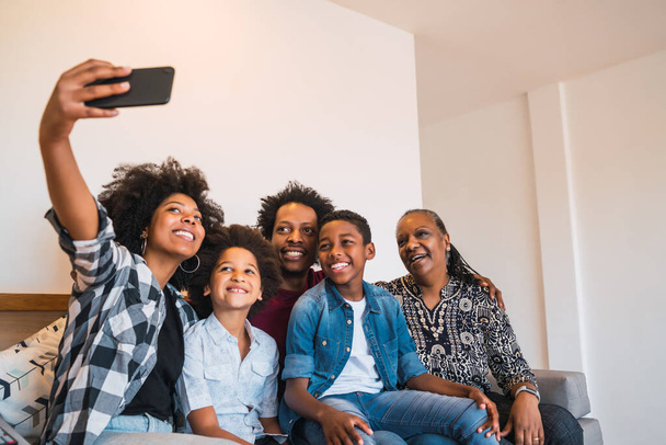 Portrait of african american multigenerational family taking a selfie together with mobile phone at home. Family and lifestyle concept. - 写真・画像