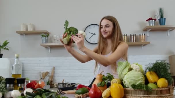Mädchen empfiehlt, rohe pflanzliche Lebensmittel zu essen. Zeigt Brokkoli und Blumenkohl. Gewichtsverlust, Ernährung - Filmmaterial, Video
