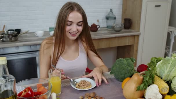 Chica comiendo brotes crudos de trigo sarraceno con nueces en la cocina. Pérdida de peso y dieta. Estilo de vida saludable - Metraje, vídeo