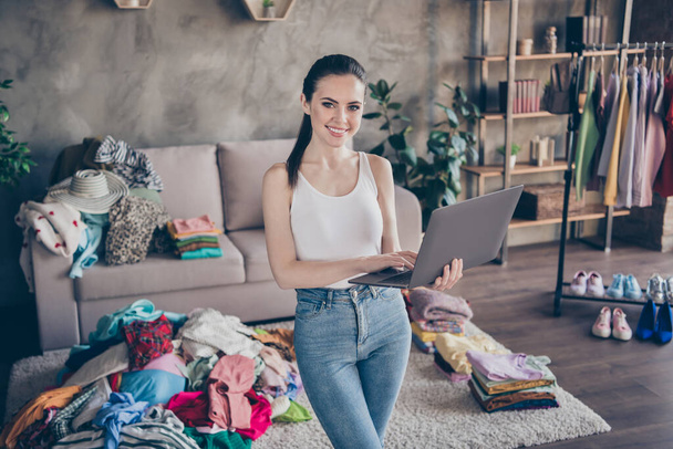 Portrait of positive cheerful girl fashion blogger use laptop search black friday online store bargain offer purchase wear denim jeans in house indoors - 写真・画像