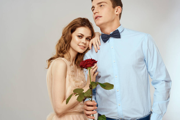 Egy szerető fiatal pár, piros rózsával a kezükben, egy kis háttérromantikával. - Fotó, kép