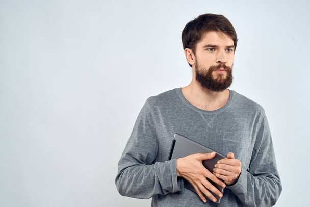 Ένας άνθρωπος σε ένα γκρι πουλόβερ ένα δισκίο στα χέρια των συναισθημάτων Internet τεχνολογία lifestyle φως φόντο - Φωτογραφία, εικόνα