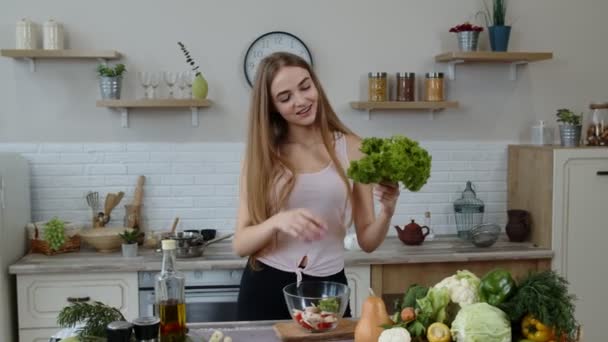 Menina dançando, se divertindo e cozinhando salada com legumes crus. Lançar pedaços de alface - Filmagem, Vídeo