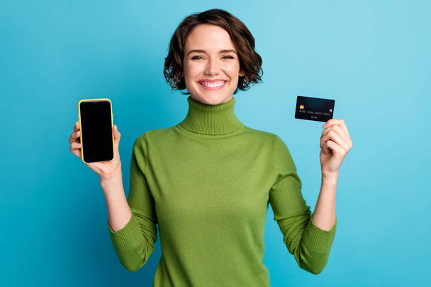 Portrait of positive girl hold credit card smartphone recommend pay buy online bank wear style stylish trendy pullover isolated over blue color background - Photo, Image