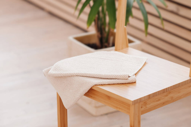 naturalny beżowy ręcznik składany na drewnianym stole łazienkowym. elementy wystroju łazienki z wykorzystaniem naturalnych materiałów. Minimalizm w renowacji - Zdjęcie, obraz