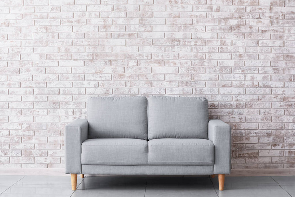 Stylish sofa near brick wall in room - Fotoğraf, Görsel