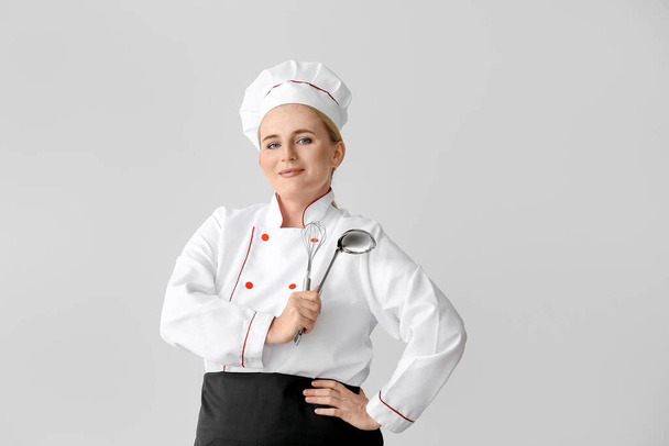 Mature female chef on grey background - Foto, Bild