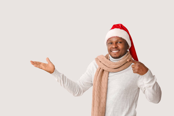 Afro-Amerikaanse man in Santa hoed op lichte achtergrond - Foto, afbeelding