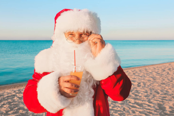 Санта Клаус з соком відпочиває на морському курорті. Різдвяна відпустка - Фото, зображення