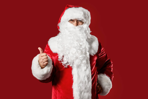 Санта Клаус показывает большой палец на цветном фоне. Рождественские каникулы - Фото, изображение