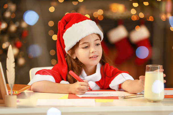 Маленька дівчинка пише листа до Санти вдома напередодні Різдва
 - Фото, зображення