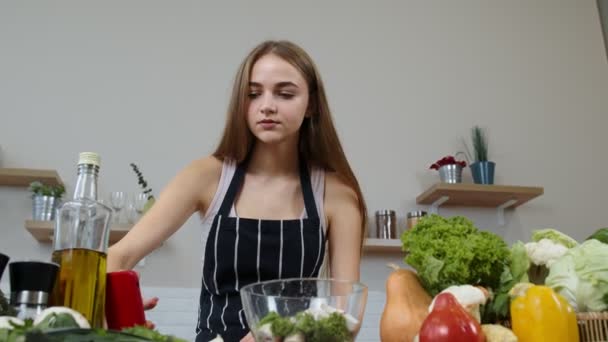 Vegan ragazza cottura insalata con verdure crude mentre cerca sul telefono cellulare per la ricetta online - Filmati, video