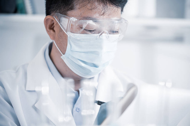 Scienziato maschio asiatico che lavora in un laboratorio. Concetto di sviluppo del vaccino. - Foto, immagini