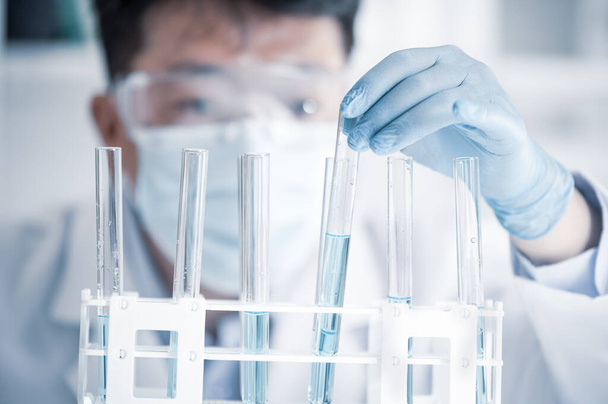 Aziatische mannelijke wetenschapper die in een laboratorium werkt. Ontwikkeling van vaccins. - Foto, afbeelding