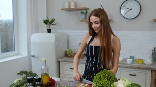 Veganerin kocht Salat mit rohem Gemüse, während sie auf dem Handy nach Online-Rezept sucht - Filmmaterial, Video