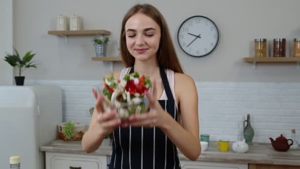gelukkig jong vrouw eten vers rauw groente salade poseren in keuken met positieve emotie - Video