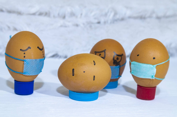 Mehrere bemalte Eier tragen Masken und trauern um einen Toten, der keine Maske trägt. Spaß an der Bewegung mit Kindern. - Foto, Bild
